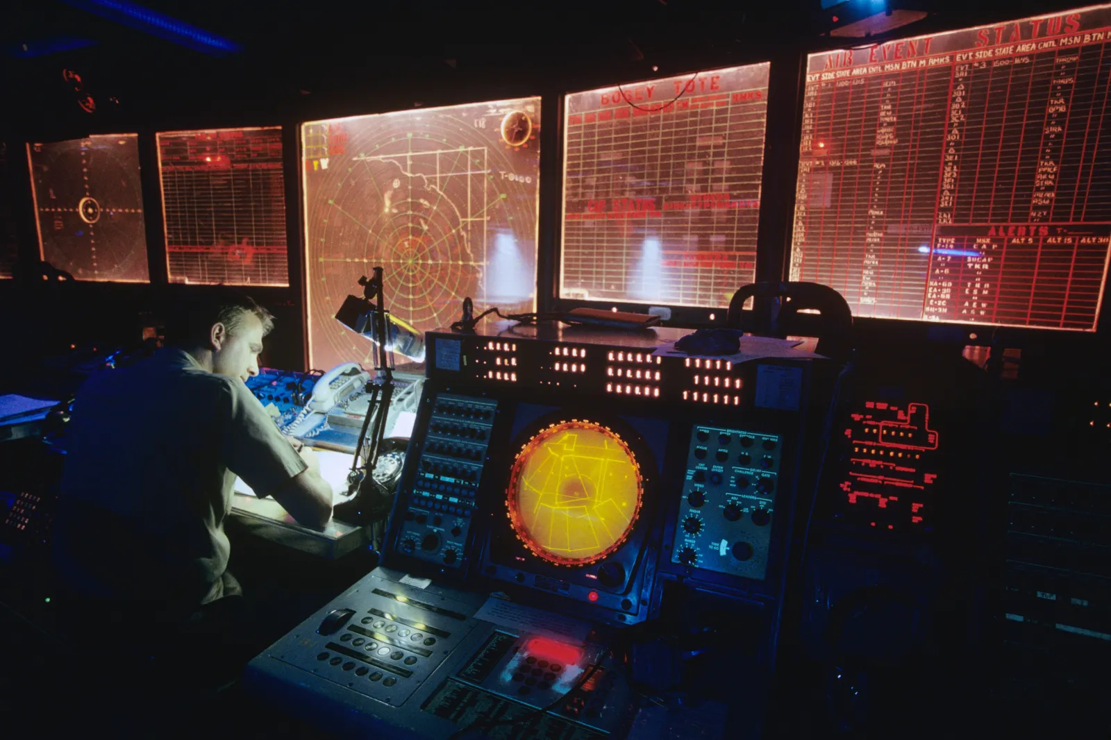 Stock image: a man studies the control desk of an aircraft carrier.