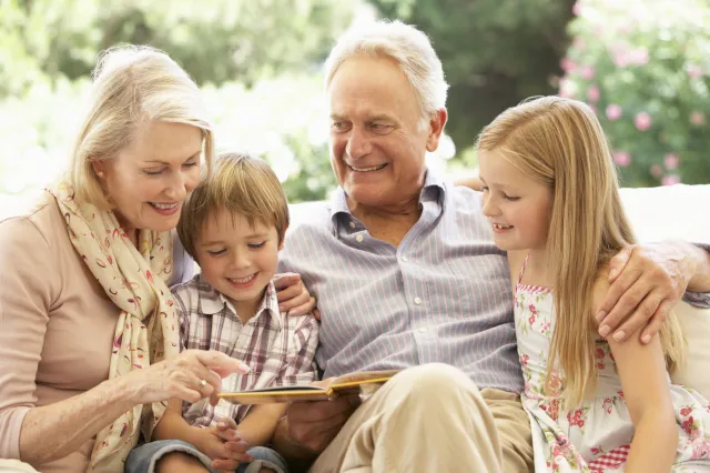 An elderly couple reads to two kids