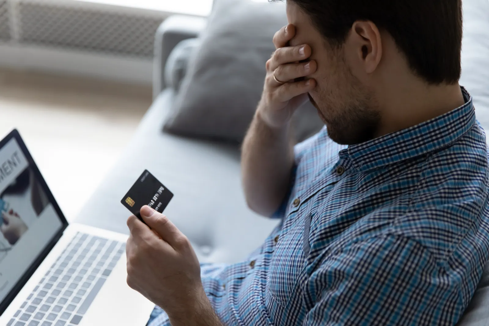 Unhappy man with credit card before laptop
