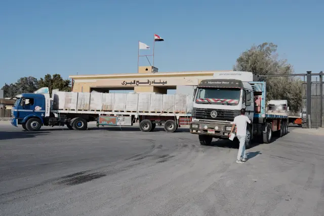 Trucks carrying humanitarian aids prepare to enter the buffer zone outside Rafah crossing between Egypt and the Gaza Strip, following an agreement between Israel and Hamas on a ceasefire, Thursday, Oct.16, 2025