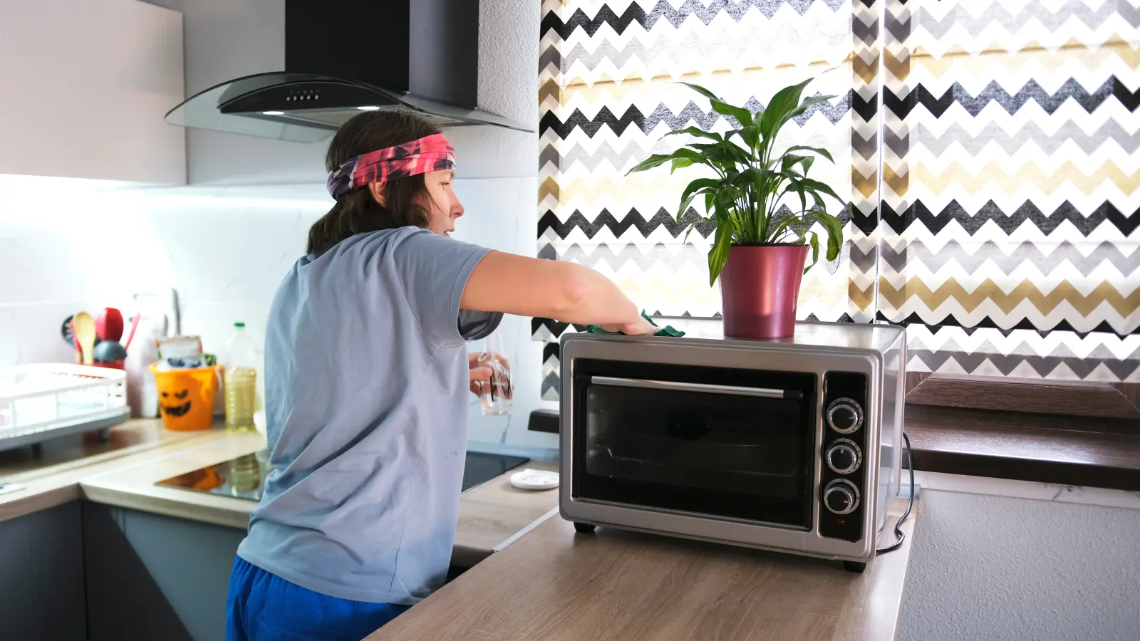 Woman wiping top of toaster oven.