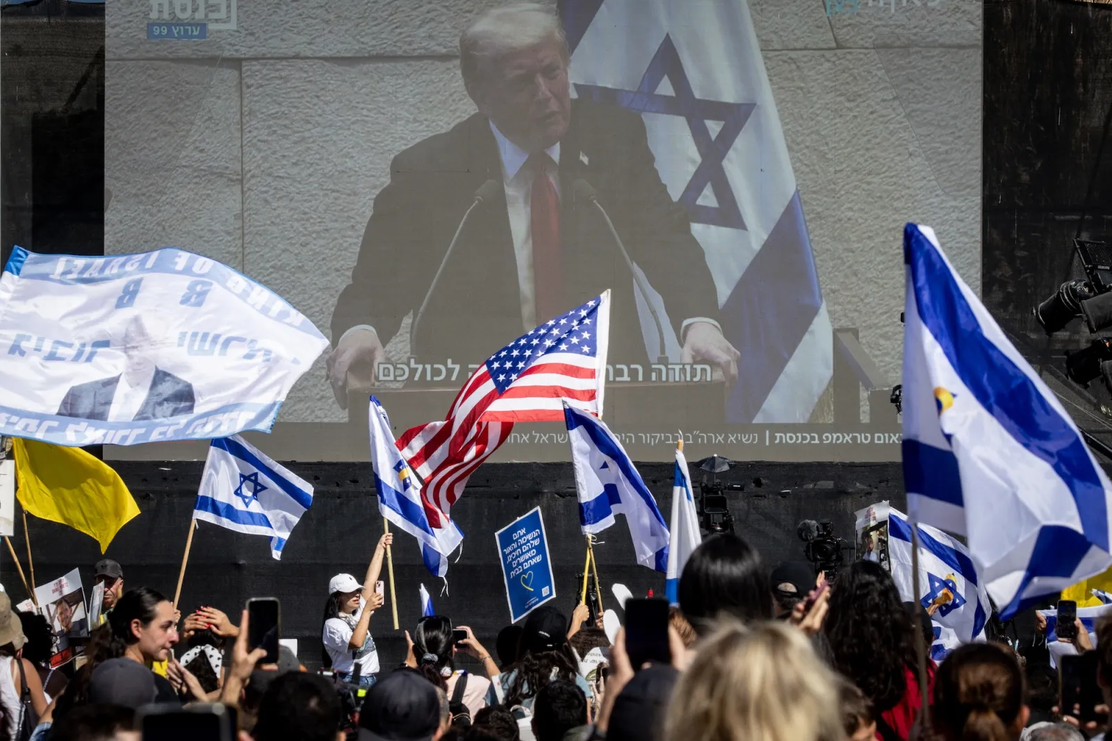TEL AVIV, ISRAEL - OCTOBER 13: People watch U.S. President Donald Trump address the Knesset, Israel's parliament, on a giant screen in Hostages Square on October 13, 2025 in Tel Aviv, Israel. The ceasefire deal between Israel and Hamas has brought an end to the two years of war that followed the attacks of Oct. 7, 2023. A condition of the deal was the immediate return of 48 hostages held in Gaza, around 20 of whom were believed to be alive. (Photo by Chris McGrath/Getty Images)