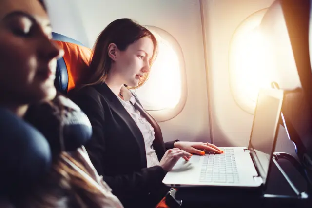 A woman looking at laptop on plane.