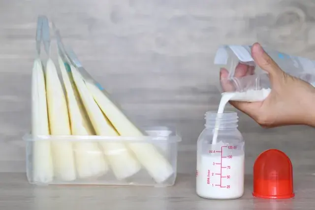 Woman pouring milk into bottles for baby.