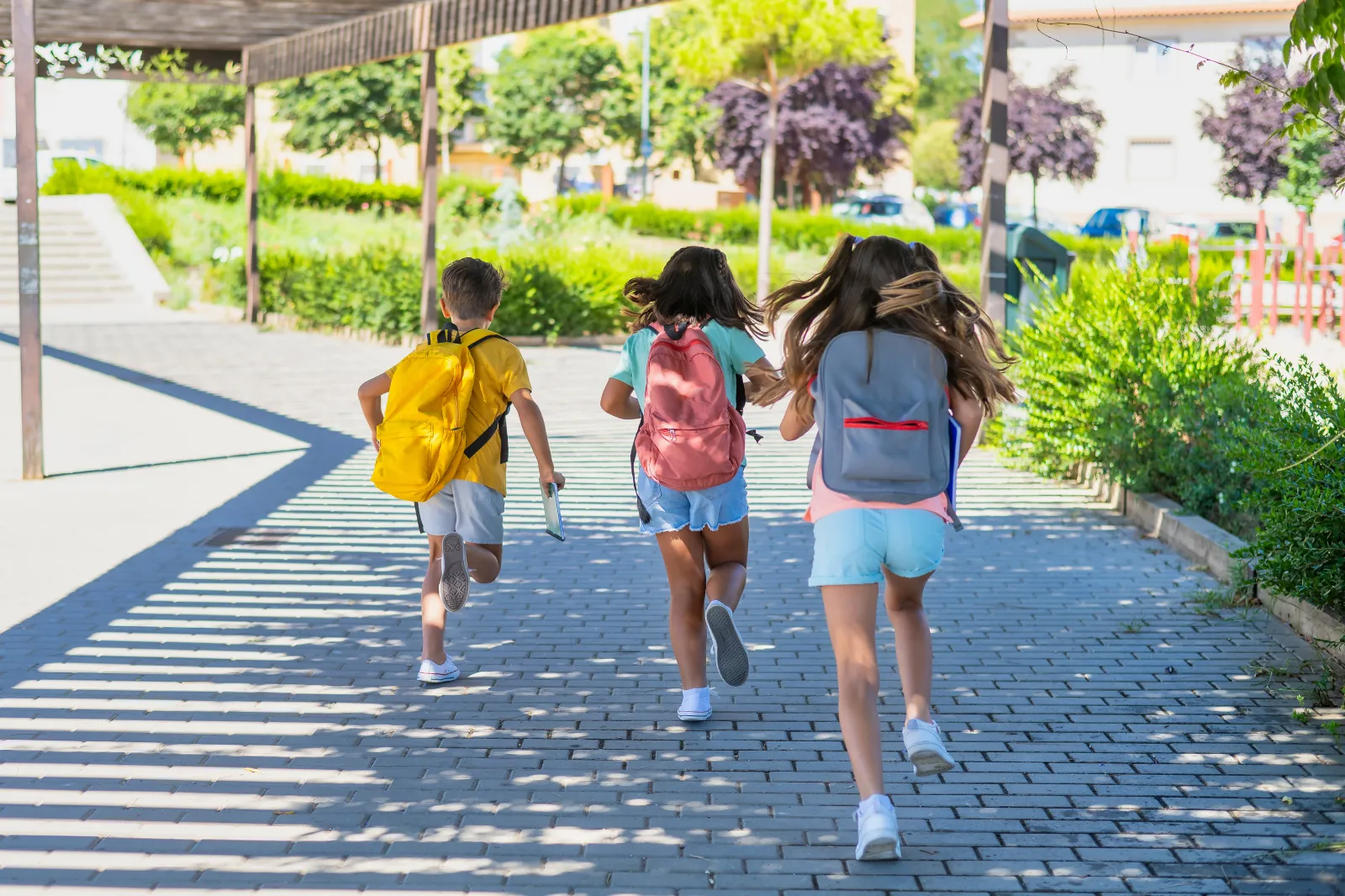 A group of children run to school with their backpacks on.