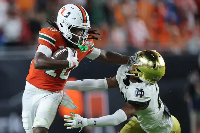 Malachi Tony #10 of the Miami Hurricanes pushes off cornerback Karson Hobbs #21 of the Notre Dame Fighting Irish