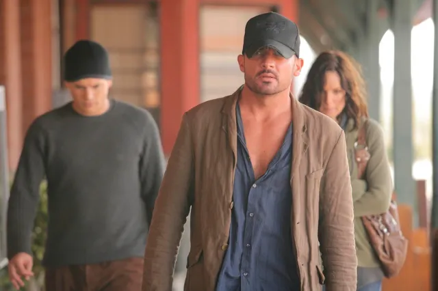 A man in a jacket and cap walks towards the camera