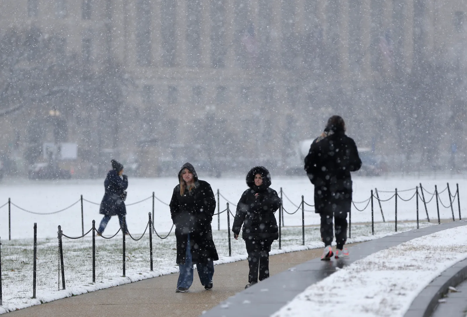 People walk on the National Mall, during the first snowfall of the winter season