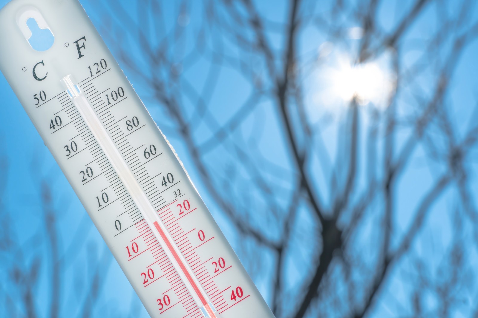 The thermometer lies on the snow and shows a negative temperature in cold weather on the blue sky.Meteorological conditions with low air and ambient temperatures.Climate change and global warming
