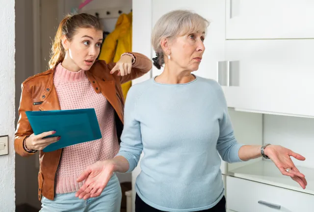 Older woman looking away from younger woman during disagreement.