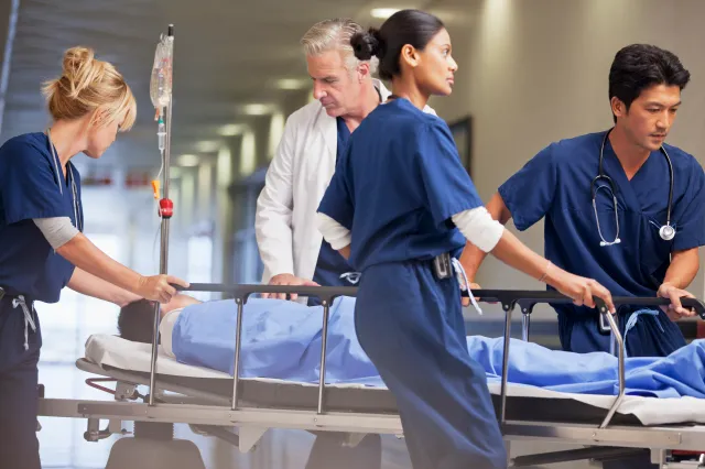 Nurses and a doctor wheel a patient through a hospital corridor.