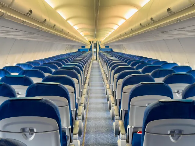 A stock image showing an aisle view of an empty commercial aircraft.