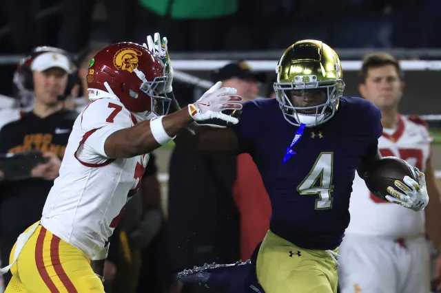 Jeremiyah Love #4 of the Notre Dame Fighting Irish stiff arms Kamari Ramsey #7 of the USC Trojans at Notre Dame Stadium