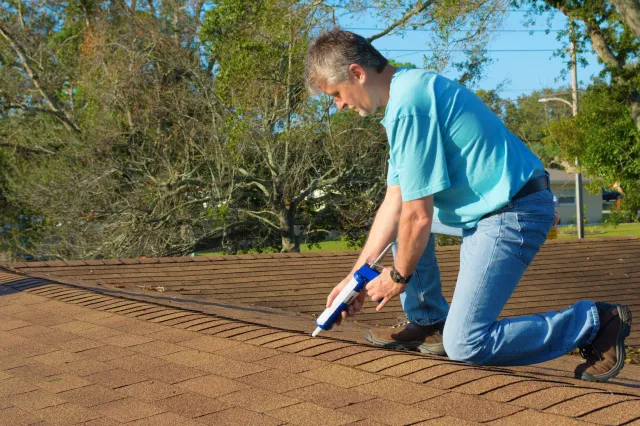 A man doing patchwork on a roof.