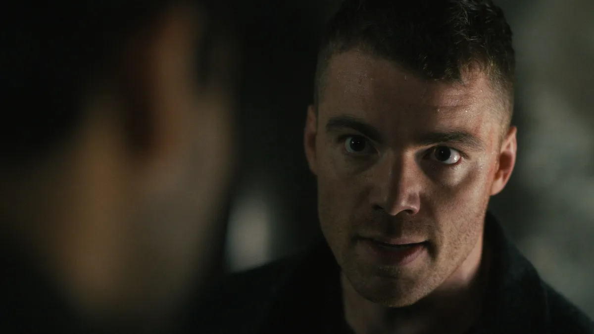 A white man with short, brown hair with a neutral expression