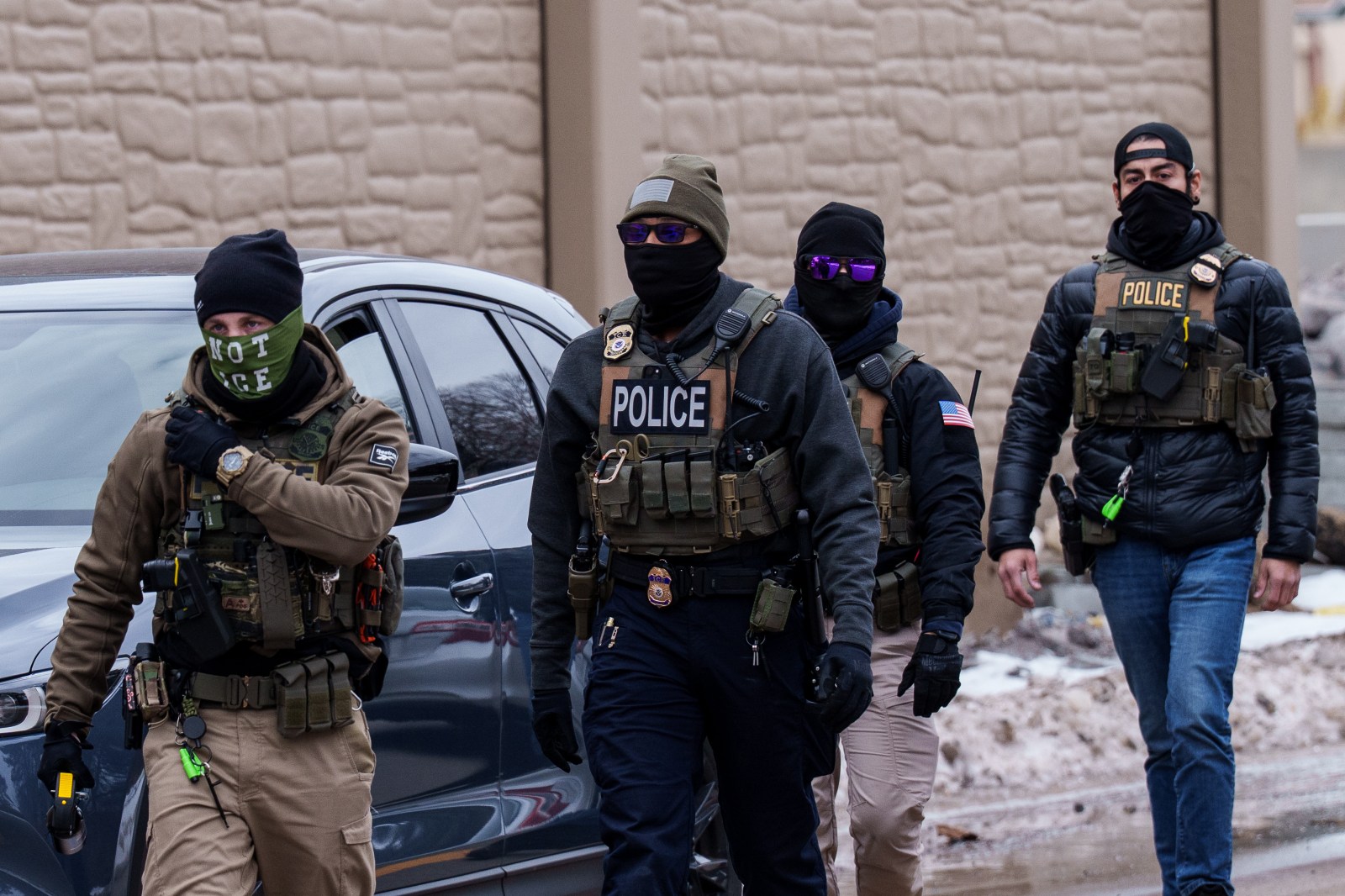 Immigration and Customs Enforcement (ICE) agents, including one wearing a ‘NOT ICE’ face covering, walk near their vehicles, Thursday, Jan. 15, 2026, in Richfield, Minn. (AP Photo/Adam Gray)
