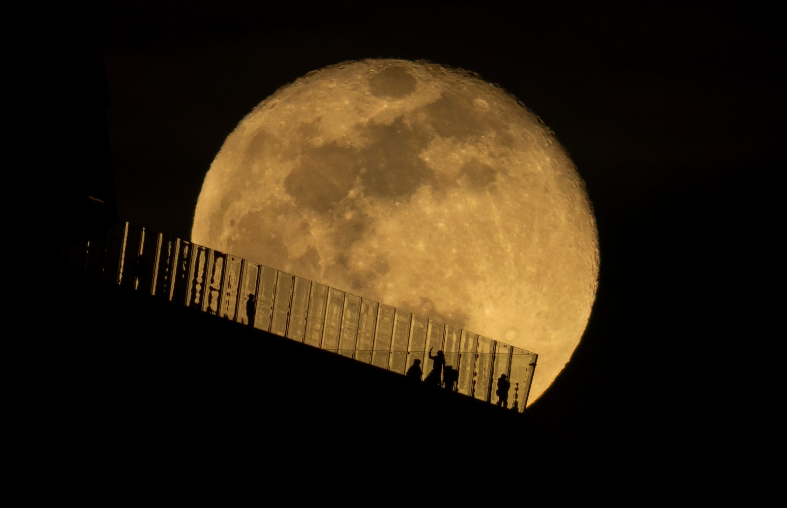 A view of the Snow Moon rising behind people at an outdoor observation deck at Hudson Yards in New York City on February 13, 2025.
