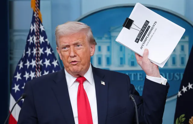 Donald Trump displays a stack of papers labeled "The White House Accomplishments" as he arrives for a press briefing in the James S. Brady Press Briefing Room of the White House on January 20, 2026 in Washington, DC.