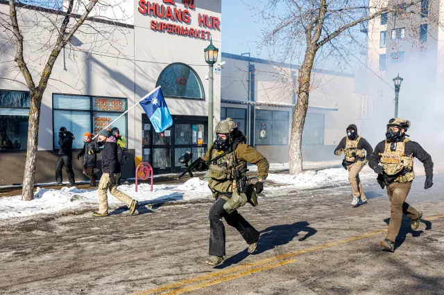 ICE agents run after protesters as a demonstrator carries Minnesota's newly adopted state flag during clashes following a fatal shooting of a man by federal agents earlier in the day, on January 24, 2026 in Minneapolis, Minnesota.