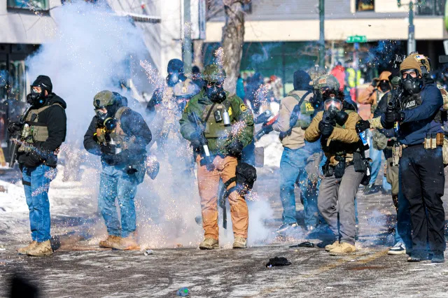 Federal agents fire flash-bang grenades as they advance toward protesters during clashes following the fatal shooting of a man by federal immigration agents earlier in the day, on January 24, 2026 in Minneapolis, Minnesota.