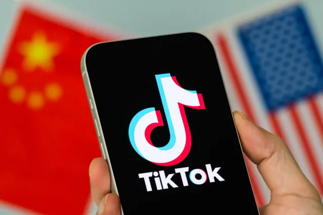 Smartphone displaying the TikTok logo, with the Chinese and U.S. flags visible in the background, on January 23, 2026, in Chongqing, China.