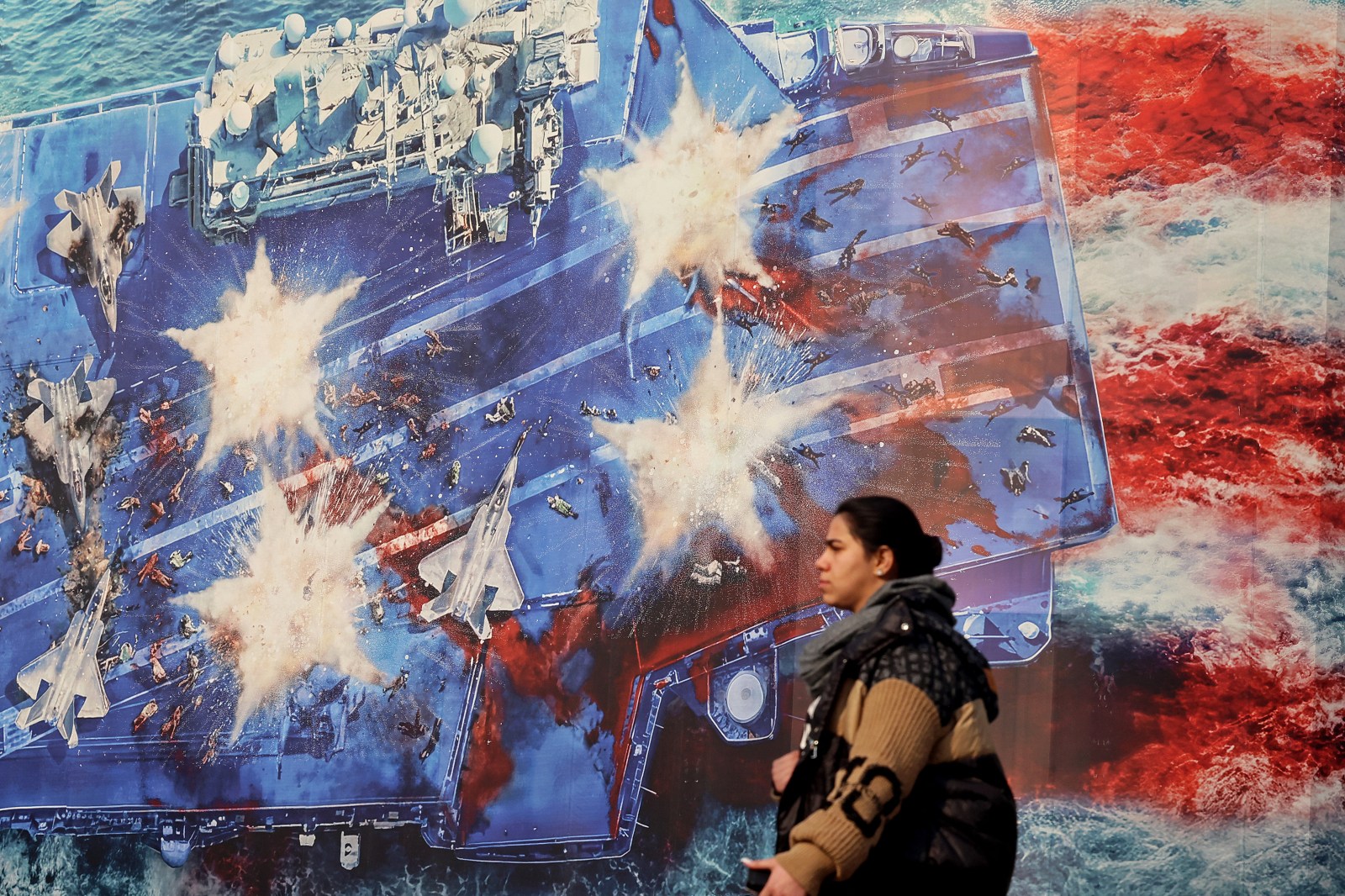 A woman walks past an anti-US billboard installed on a building at the Enqelab Square in Tehran on January 26, 2026. (Photo by ATTA KENARE / AFP via Getty Images)
