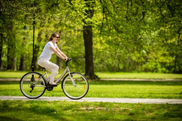 A woman cycling through a park.