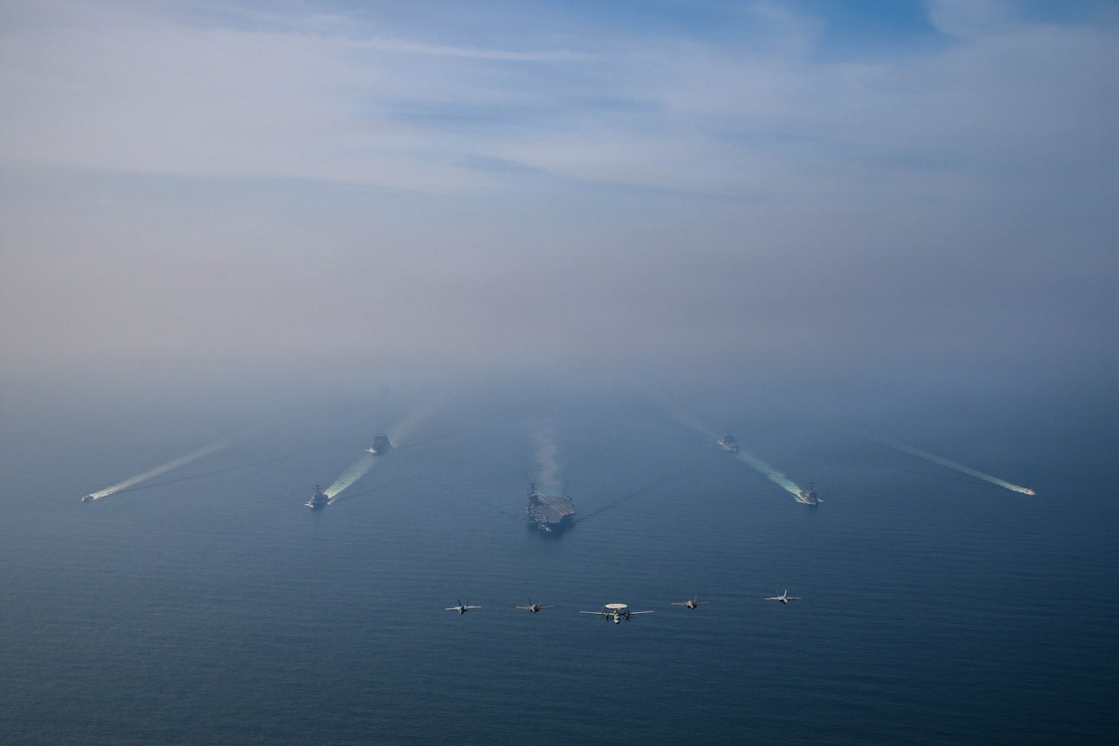 Nimitz-class aircraft carrier USS Abraham Lincoln and its strike group sail in formation in the Arabian Sea while aircraft fly overhead, on February 6, 2026.