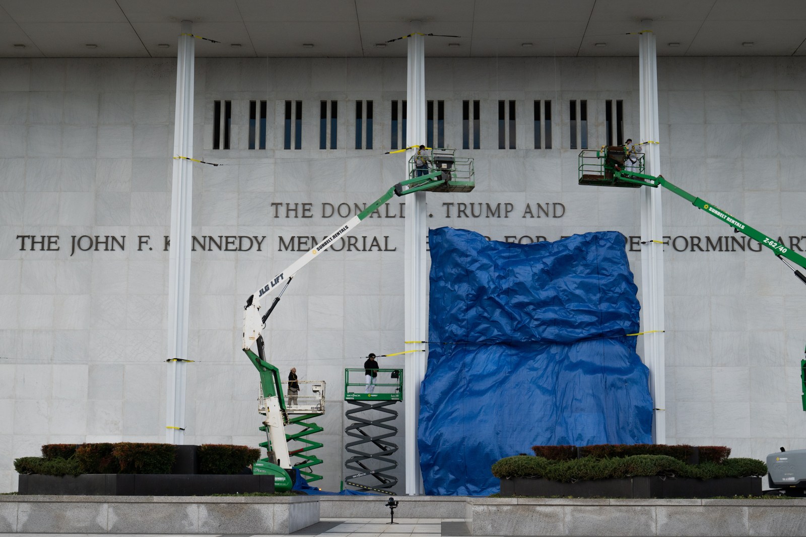 A tarp covering the the Kennedy Center is dropped as workers finish installing President Donald Trump’s name on the facade of the building in Washington, D.C. on Friday, December 19, 2025. (Photo by Annabelle Gordon/Sipa USA)(Sipa via AP Images)
