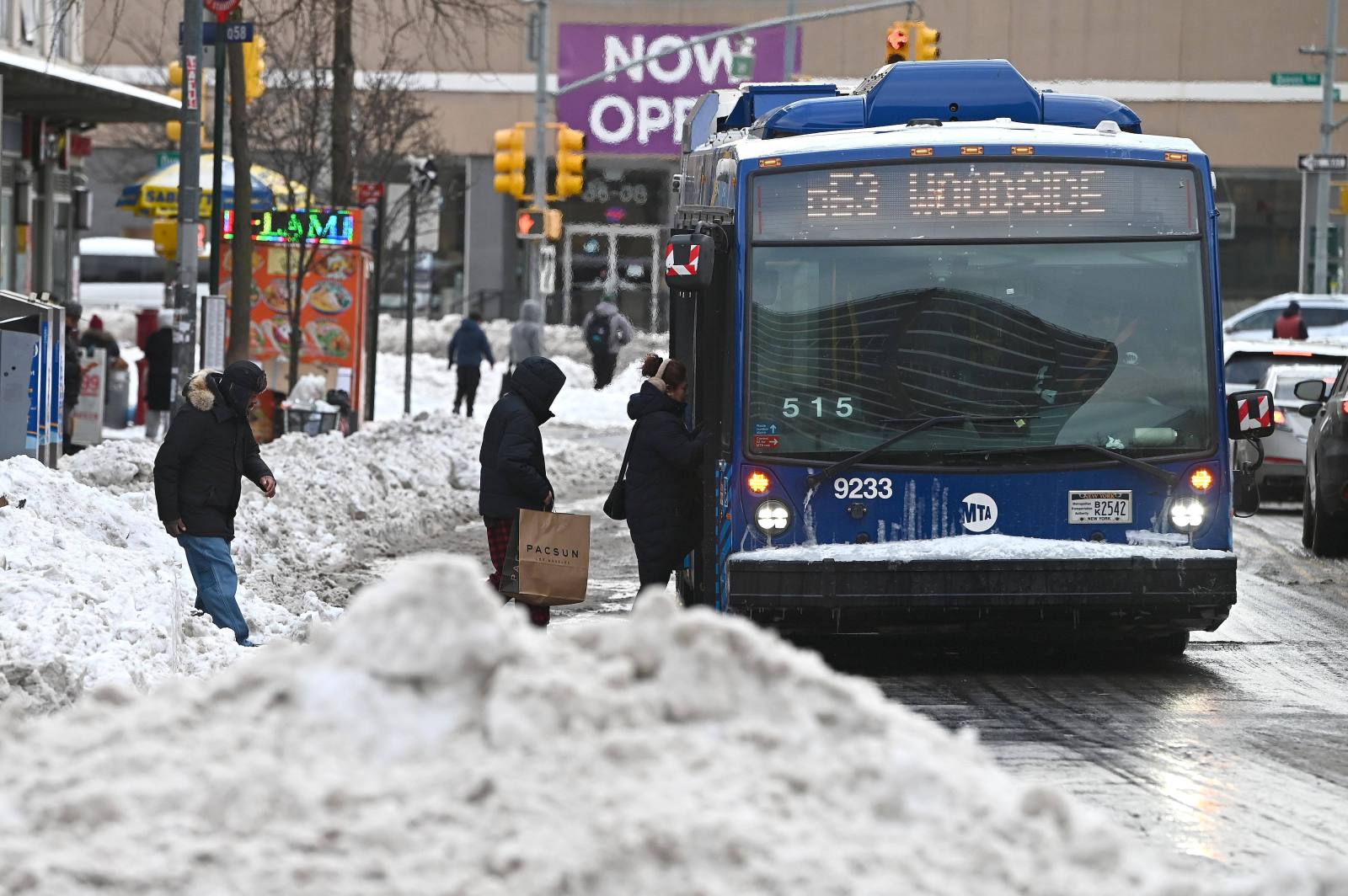 Commuters walk over berms of snow created by snow plows to board their bus in the New York City Borough of Queens, NY, January 26, 2026. New York City and it’s five boroughs saw more than 10 inches of snow fall at a rate of 1 to 2 inches per hour with freezing gusts of wind after a massive winter storm blanketed the US East Coast. (Photo by Anthony Behar/Sipa USA)(Sipa via AP Images)