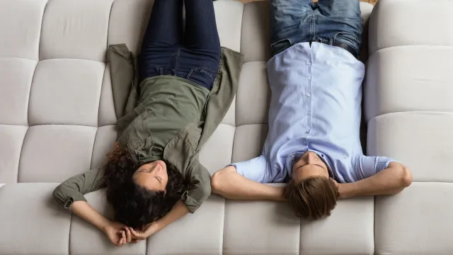 A couple laying down on a large sofa.
