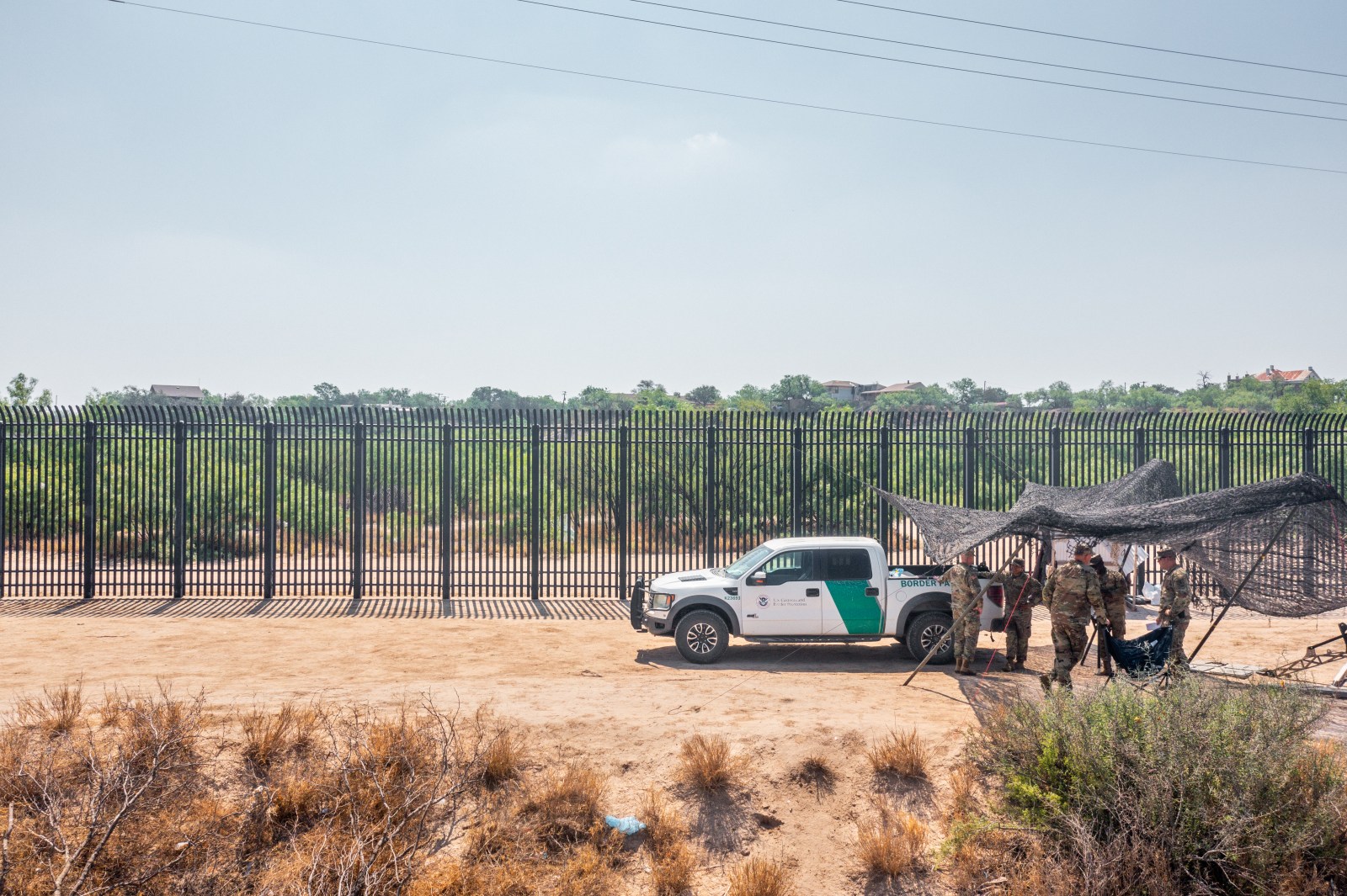 EAGLE PASS, TEXAS – JUNE 04: In an aerial view, National Guard members stand under shade while on patrol near the banks of the Rio Grande river on June 04, 2024 in Eagle Pass, Texas. President Biden is expected to sign an executive order that would prohibit migrants who illegally cross the southern border from claiming asylum in the U.S. The move comes after the collapse of a bipartisan Senate agreement on securing the border. (Photo by Brandon Bell/Getty Images)