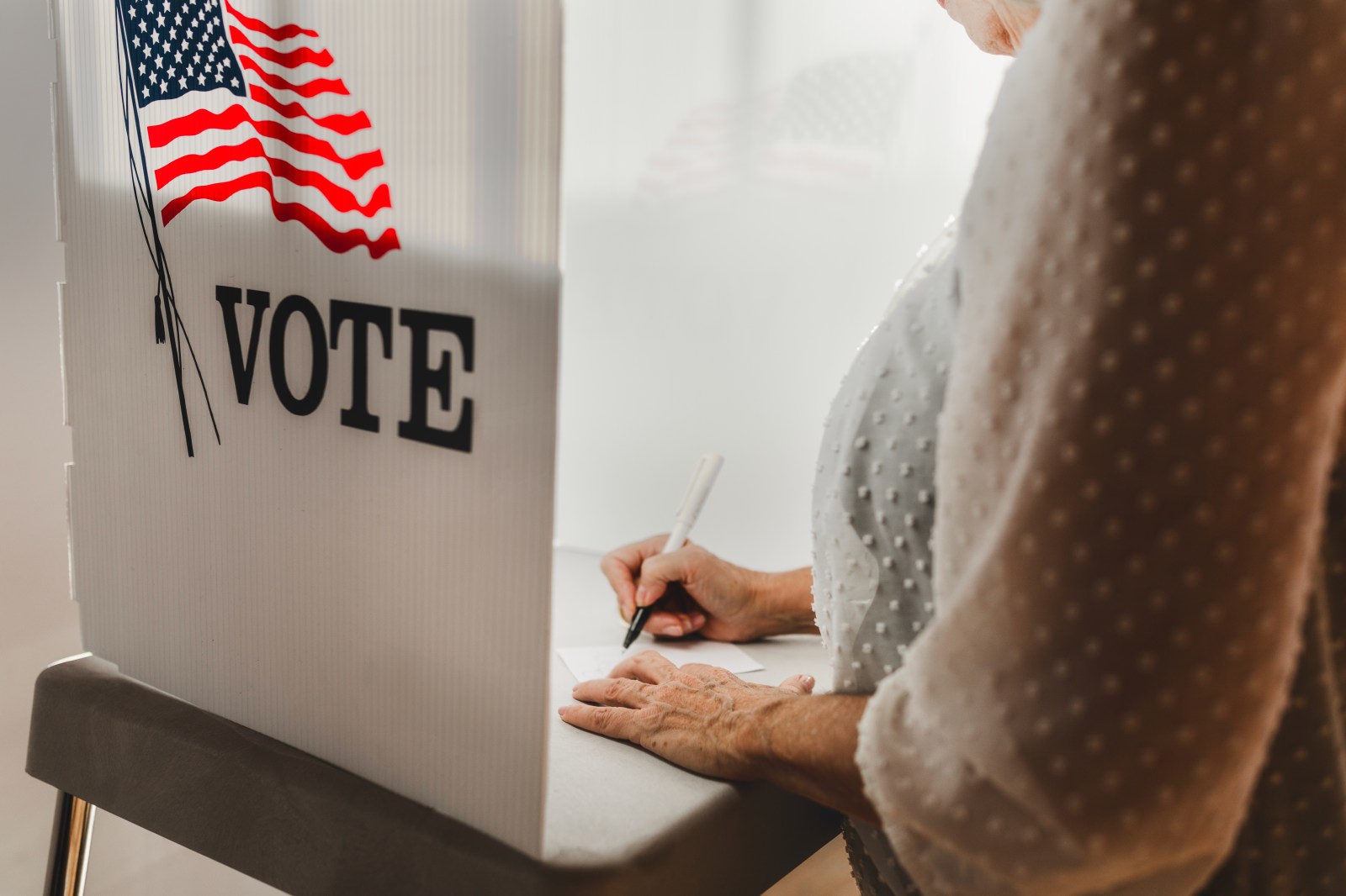 Woman voting in a privacy booth on U.S. election day. 

