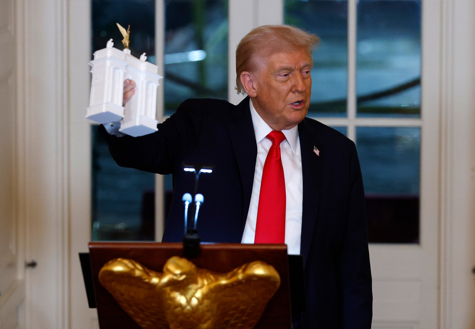 U.S. President Donald Trump holds models of an arch as he delivers remarks during a ballroom fundraising dinner in the East Room of the White House on October 15, 2025 in Washington, DC.