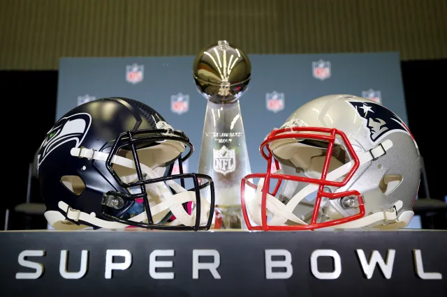 The Vince Lombardi Trophy is framed by the Seattle Seahawks and New England Patriots helmets during Super Bowl LX Opening Night.