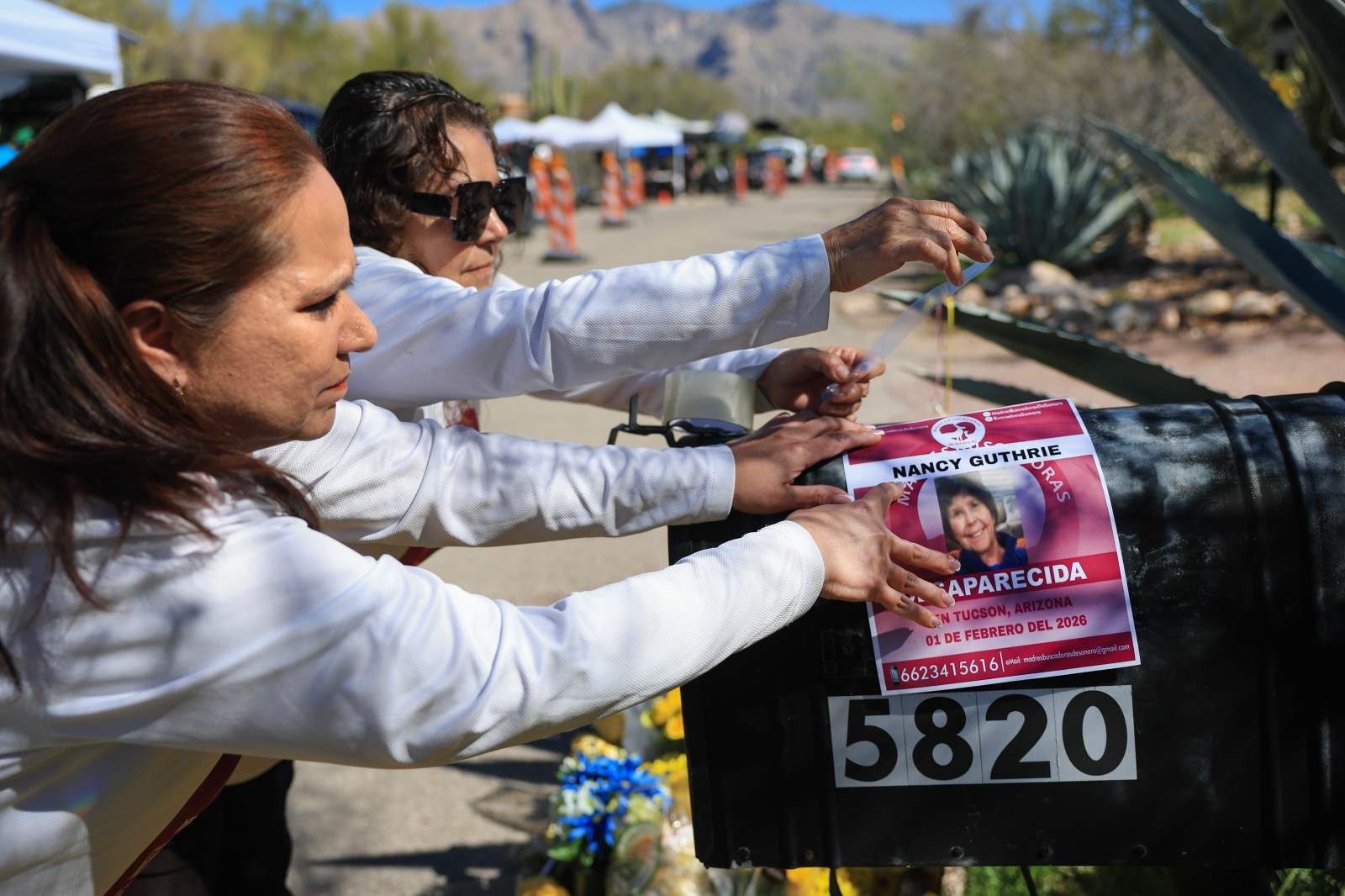 TUCSON, ARIZONA – FEBRUARY 21: Rachel Navarro (L) and Lidia Hernandez, who are part of the Madres Buscadoras De Sonora (Searching Mothers of Sonora), place a flyer that reads, ‘Nancy Guthrie Desparecida’ (Disappeared) on the mailbox of Nancy Guthrie’s residence on February 21, 2026, in Tucson, Arizona. The organization is dedicated to finding lost people in the Mexican state of Sonora and, sometimes, in other areas. Law enforcement officials continue to search for Nancy Guthrie, the 84-year-old mother of U.S. journalist and television host Savannah Guthrie, after she went missing from her home on the morning of February 1st. An anonymous donor contributed $100,000 to the total reward offered in the Nancy Guthrie case, bringing it to over $200,000.  (Photo by Joe Raedle/Getty Images)