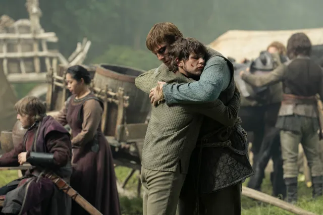 The two embrace tightly in the center of the busy, outdoor camp.