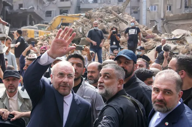 Iran's parliament speaker Mohammad Bagher Qalibaf, left, waves to residents as he visits the site of an Israeli airstrike in Beirut, Lebanon, on Oct. 12, 2024.