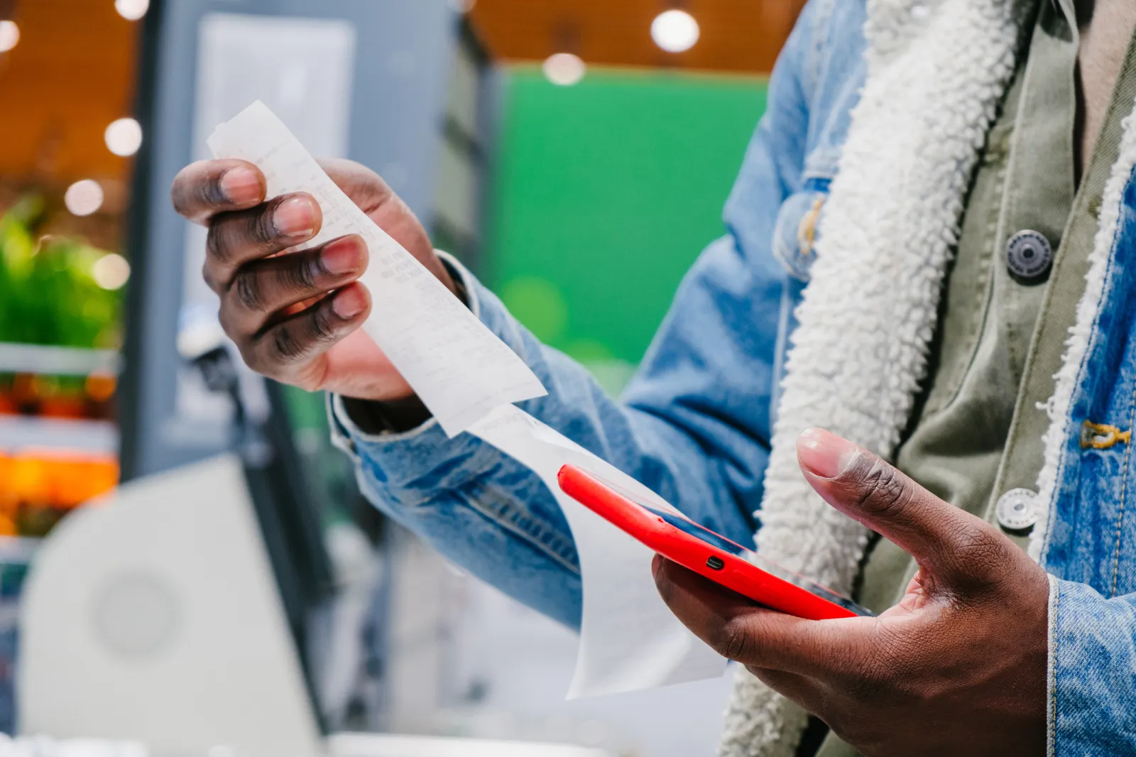 Stock image: A shopper checks receipt total while holding a phone.