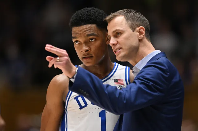 Head coach Jon Scheyer huddles with Caleb Foster #1 of the Duke Blue Devils