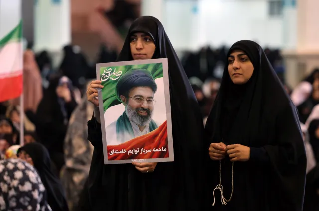 An Iranian woman holds a picture of Iranian supreme leader Ayatollah Mojtaba Khamenei during Eid al-Fitr prayers. (Photo by AFP via Getty Images)