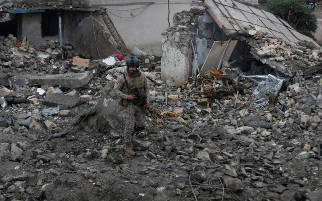 An Iraqi soldier stands guard at the site of a destroyed healthcare center in the Habbaniyah military base, which was targeted by in an airstrike killing seven security personnel and wounding 13 others, in Habbaniyah, west of Baghdad on March 26, 2026.