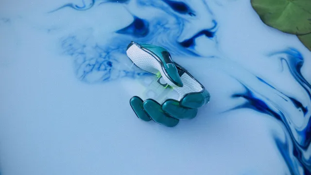 A robotic hand partially submerged in swirling blue and white liquid.