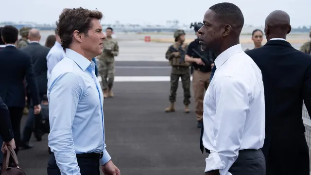 Two men stand opposite each other in shirts on an airport runway