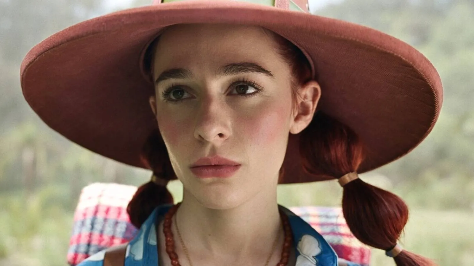 A woman with red hair and a red, wide-brimmed hat