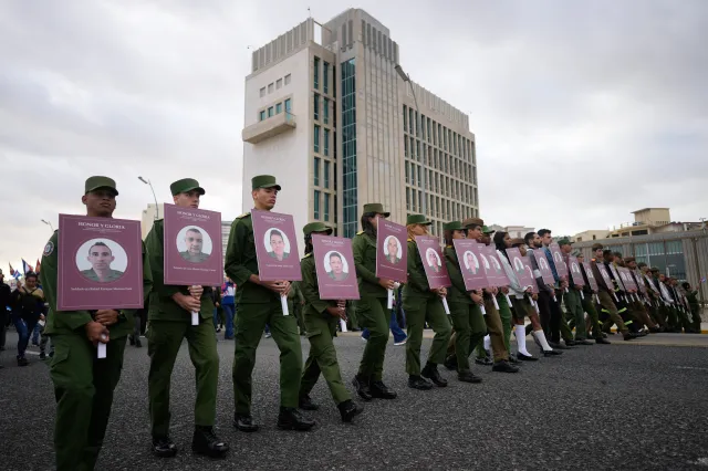 Soldiers carry photos of Cuban military personnel killed during the U.S. operation in Venezuela that captured Venezuelan President Nicolás Maduro, during a rally outside the U.S. Embassy in Havana on January 16, 2026.
