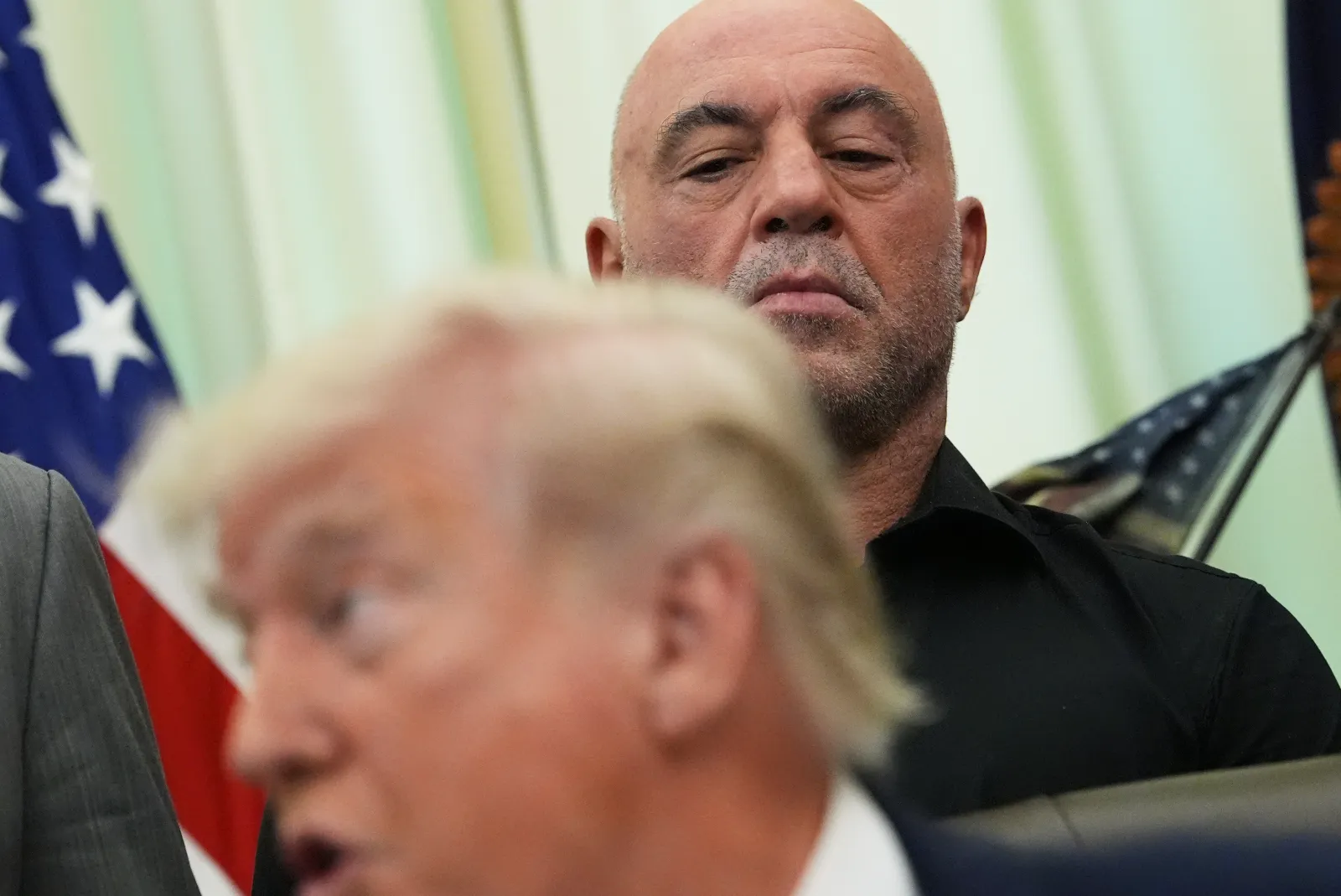 Joe Rogan listens to President Donald Trump speak in the Oval Office of the White House on April 18, 2026.
