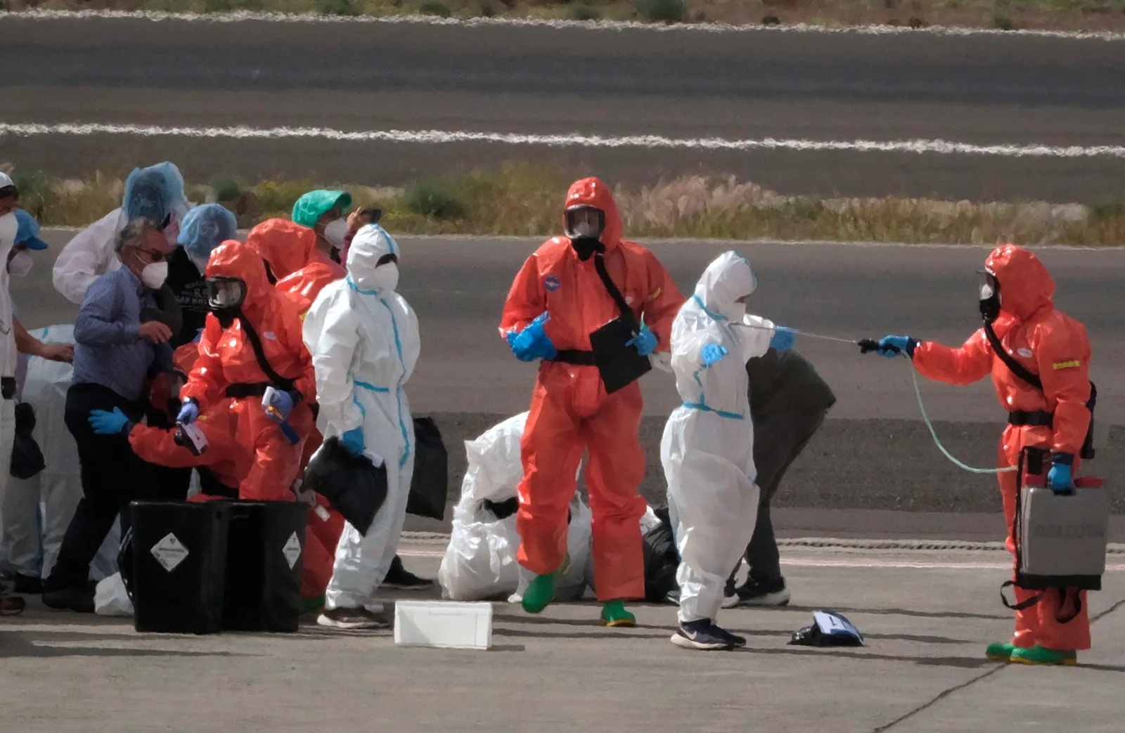 Passengers are sprayed with disinfectant by Spanish government officials before boarding a plane after disembarking from the hantavirus-stricken cruise ship MV Hondius at Tenerife airport in the Canary Islands, Spain, Sunday, May 10, 2026. (AP Photo/Arturo Rodriguez)