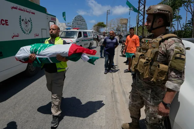 A volunteer paramedic carries a body, one of the six family members killed on Wednesday when their car was struck in an Israeli airstrike on a highway as they fled their village, during a funeral procession in Tyre, Lebanon, on May 29, 2026.