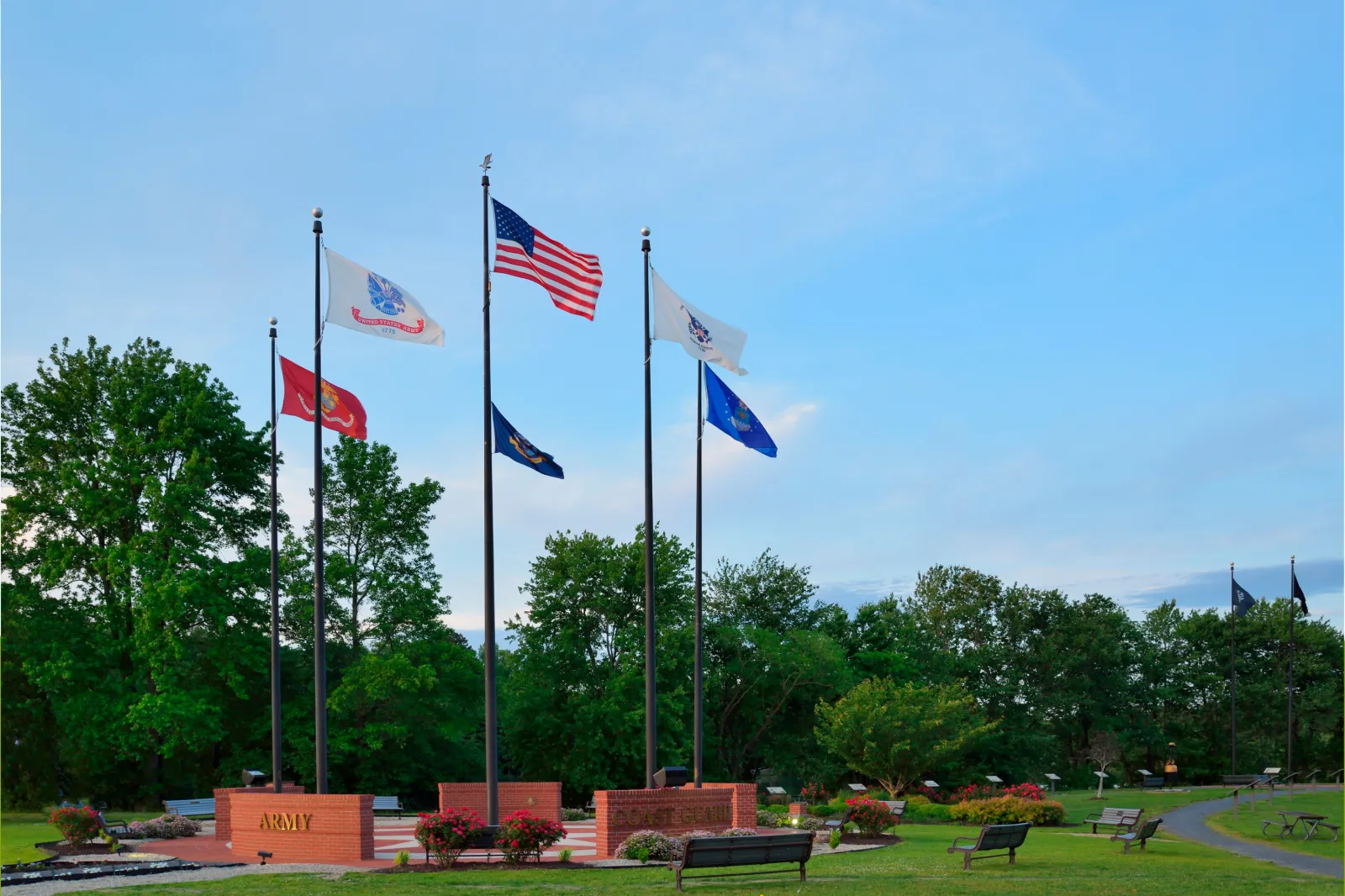 The flags of the Armed Forces and the U.S. fly against the evening sky at the Worcester Veterans Memorial in Ocean Pines, Maryland.